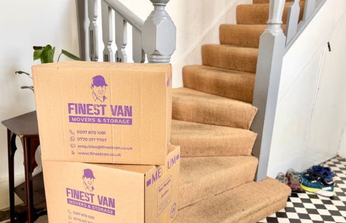 Branded moving boxes at bottom of staircase during flat move without lift in London